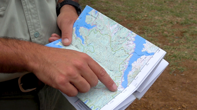 A hand holding a map of Lake Eildon and pointing out Delatite Arm Reserve